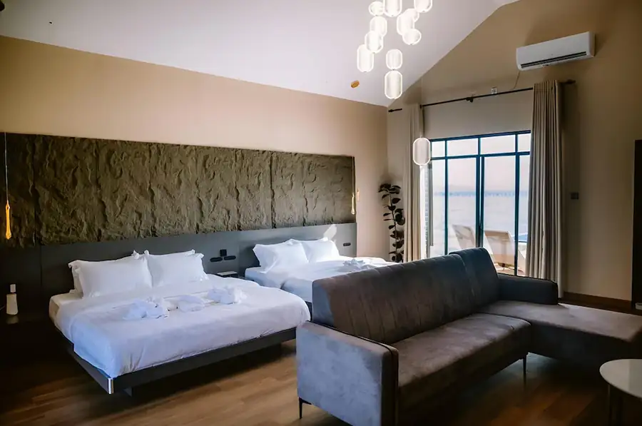 Wide interior view of the Family Room at Turtle Seaweed Resort showing two comfortable beds, a sectional sofa, and balcony access.
